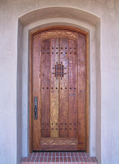 Arched rustic door with carving and wrought iron grill